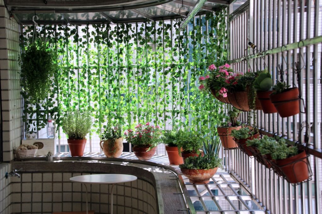 A balcony wall with a vertical garden and railing planters lit by string lights, highlighting plant and lighting balcony decoration ideas.