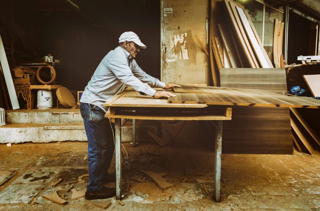 Hands using a drill to drive a screw into a wooden box corner, part of a beginner carpentry project.