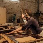 Person using a hand saw and square to cut a board, demonstrating basic tools used for simple woodworking projects for beginners